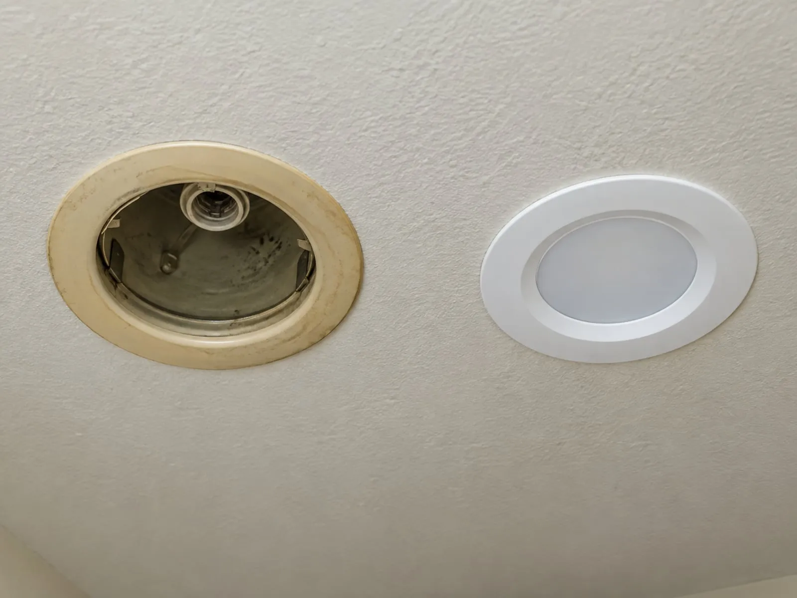 Old yellowed recessed can beside a new white LED retrofit trim